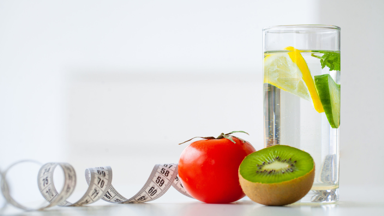 Diet. Fitness and healthy food diet concept. Balanced diet with fruit. Fresh fruit, and glass water, measuring tape on white background. Closeup